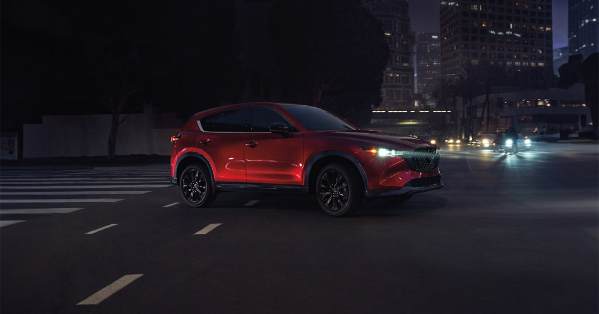 Red Mazda CX-5 driving through city streets at night
