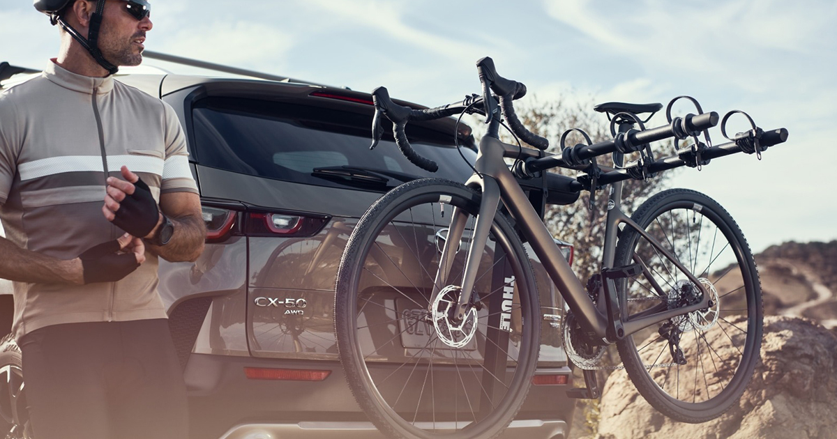 Mazda CX-50 rear view with bike rack and cyclist preparing ride