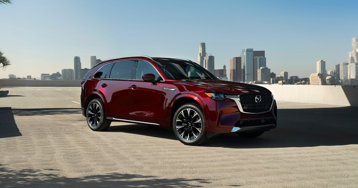 Large SUV parked on a rooftop in daylight, with a city skyline in the distance.
