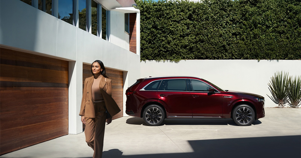 Side profile of red Mazda CX-90 SUV parked at modern home