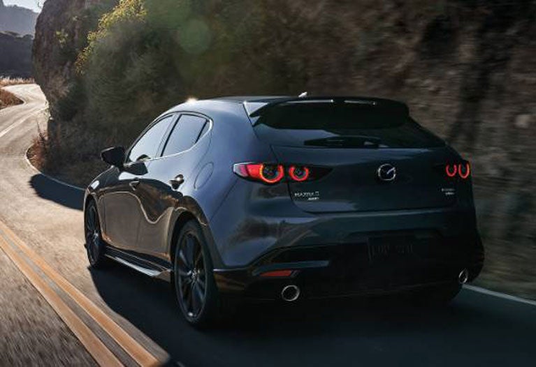 A modern hatchback back view moving on road.