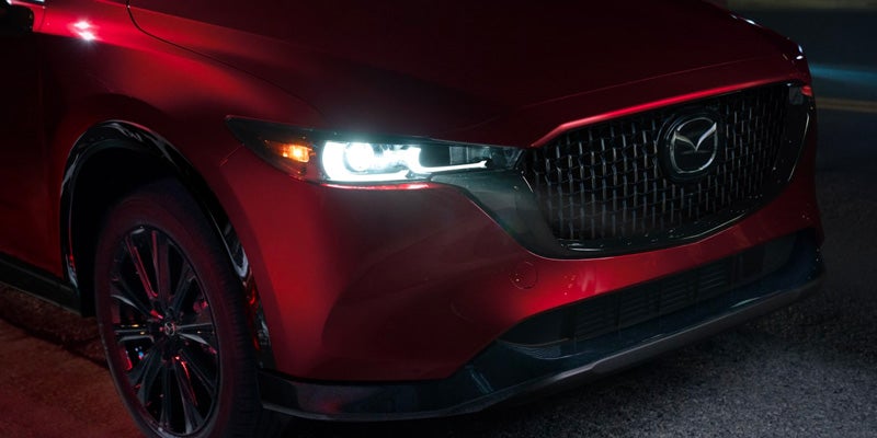 Front grille and headlight of a red Mazda SUV.